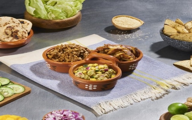 Tres guisados en cuencos de barro, sobre mantel azul.